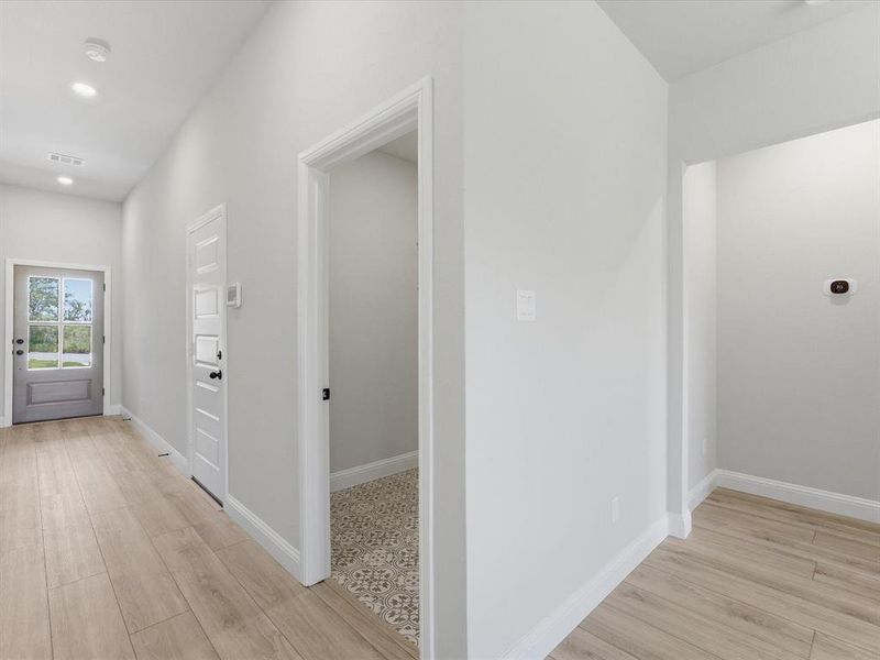 Hallway featuring wood-finish flooring, recessed lighting, and a paneled entry door with frosted glass Hallway featuring wood-finish flooring, recessed lighting, and a paneled entry door with frosted glass