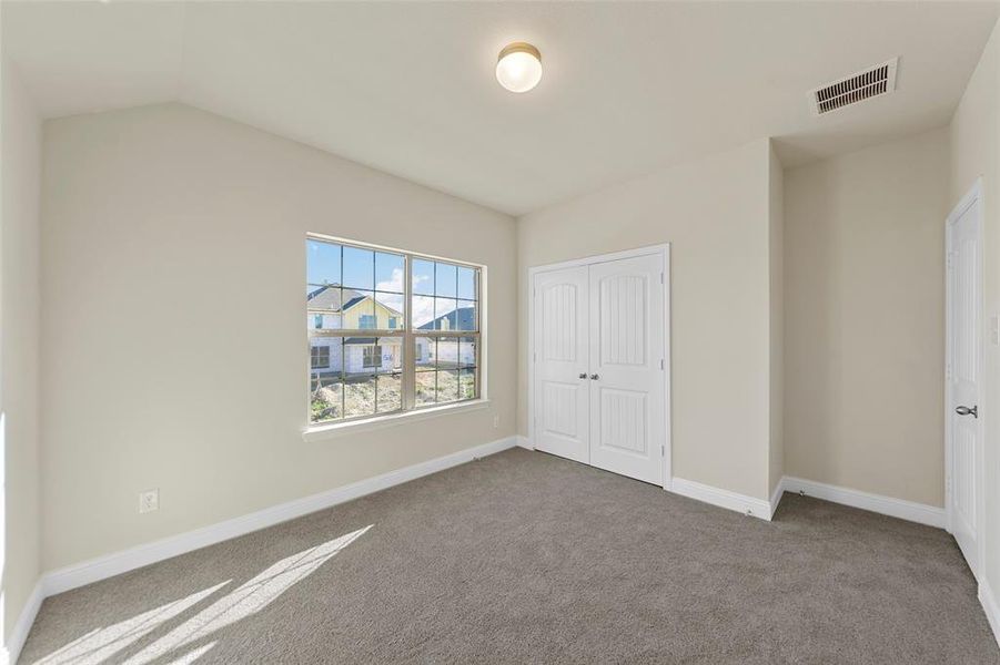 Unfurnished bedroom with carpet flooring, a closet, and lofted ceiling