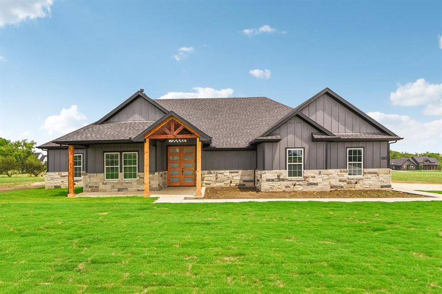 Modern farmhouse style home with board and batten siding, a front lawn, french doors, and stone siding Modern farmhouse style home with board and batten siding, a front lawn, french doors, and stone siding