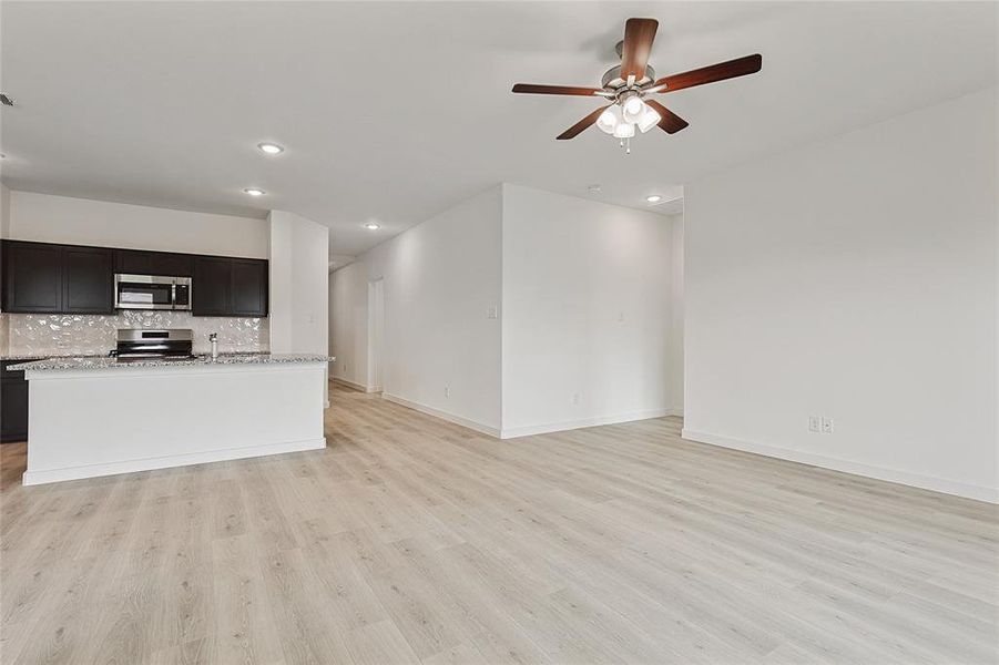 Unfurnished living room with light hardwood / wood-style floors and ceiling fan