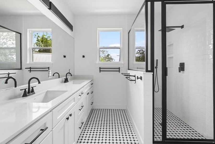Bathroom featuring double vanity, a stall shower, and plenty of natural light