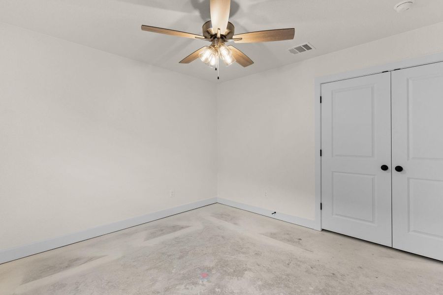 Unfurnished bedroom featuring concrete floors, a closet, and a ceiling fan Unfurnished bedroom featuring concrete floors, a closet, and a ceiling fan