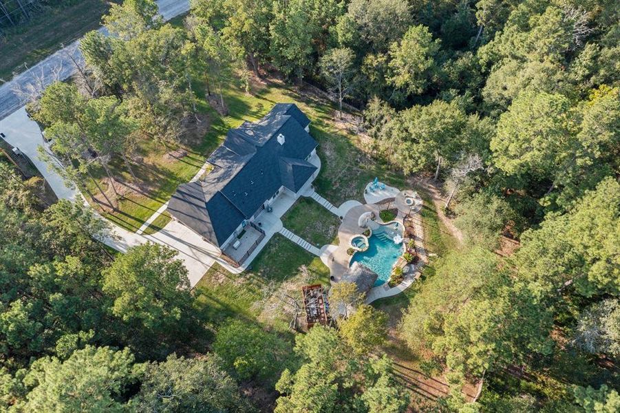 This birds-eye view shows the position of the home and pool set far back from the road, as well as the fence behind the pool. The property extends an acre behind the divider fence and includes a lovely stream.