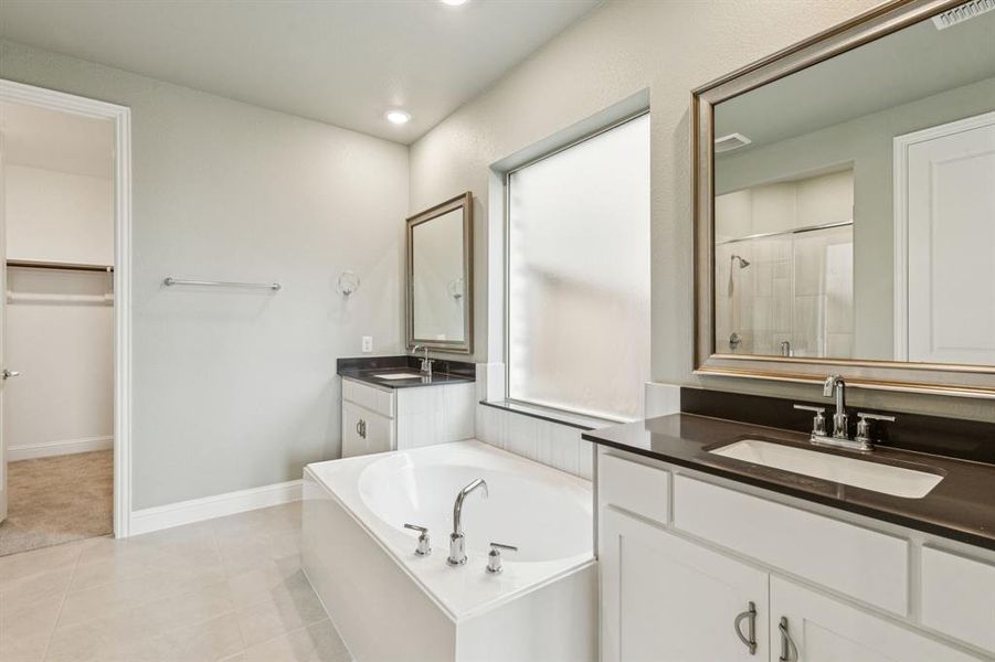Full bathroom featuring a garden tub, two vanities, a tile shower, a spacious closet, and recessed lighting