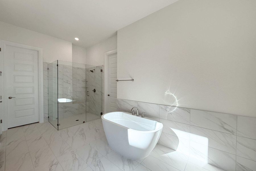Full bathroom featuring a soaking tub, light marble finish flooring, tile walls, a marble finish shower, and wainscoting