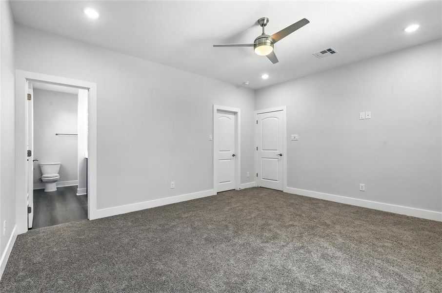 Unfurnished bedroom with dark colored carpet, recessed lighting, ensuite bathroom, and ceiling fan