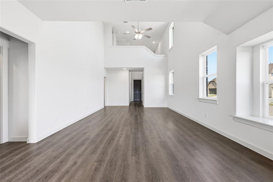 Unfurnished living room with dark wood-type flooring, high vaulted ceiling, and ceiling fan Unfurnished living room with dark wood-type flooring, high vaulted ceiling, and ceiling fan