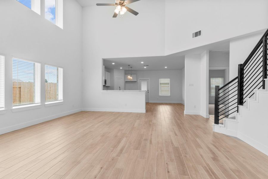 Dramatic two-story family room filled with natural light from soaring windows, creating a bright and airy atmosphere. **Image Representative of Plan Only and May Vary as Built**.