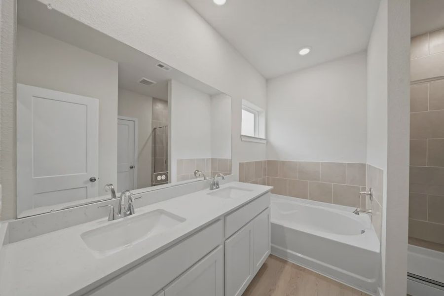A bathroom with a tub sink and a mirror. A bathroom with a tub sink and a mirror.