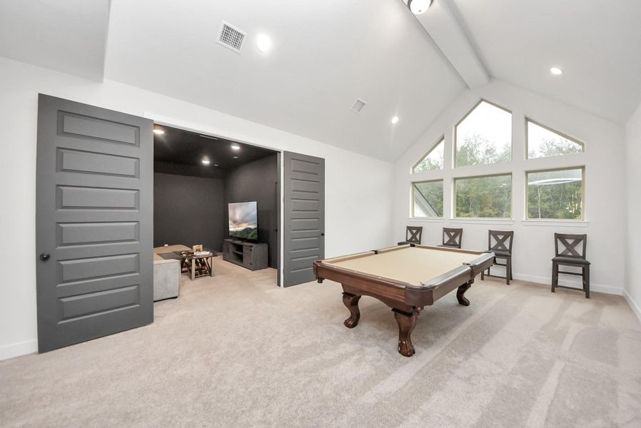 Bright upstairs game room open to the living room downstairs, featuring vaulted ceilings and an adjoining theatre room for the perfect entertainment setup.