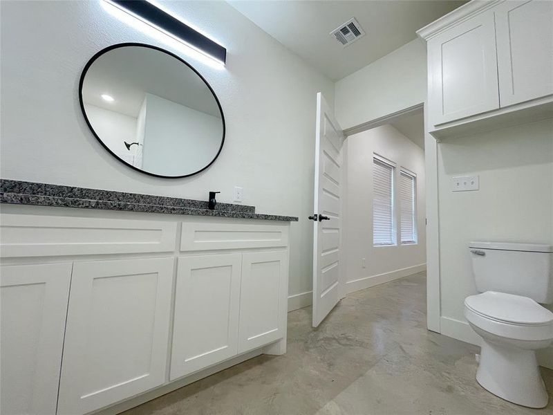 Bathroom with vanity, concrete flooring, and toilet