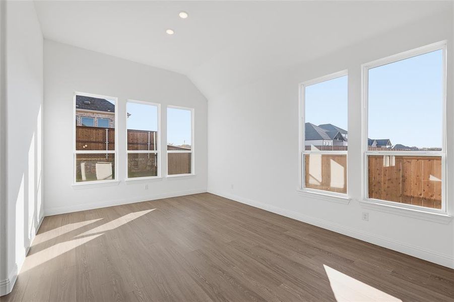 Unfurnished room with light wood-type flooring, lofted ceiling, and recessed lighting Unfurnished room with light wood-type flooring, lofted ceiling, and recessed lighting