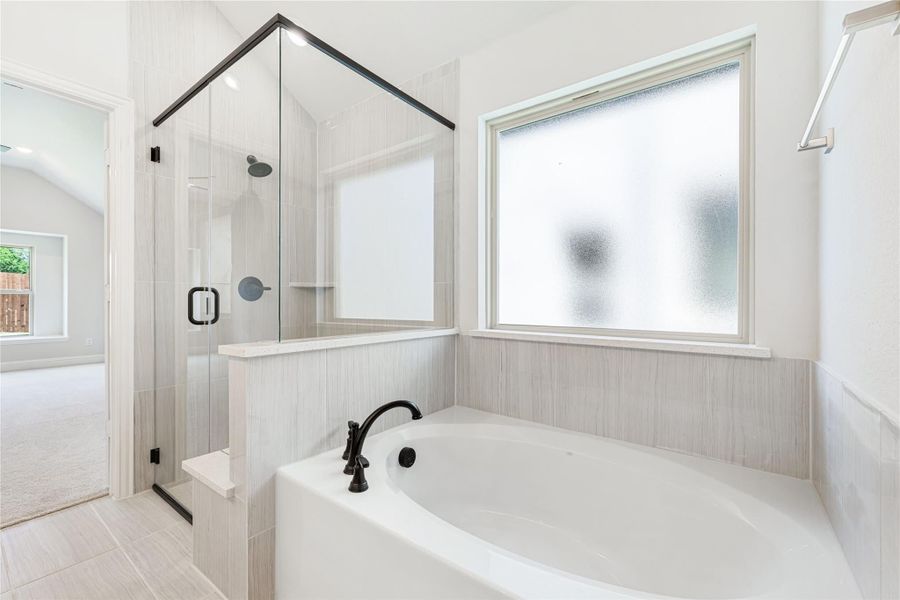 Bathroom with soaking tub, glass-enclosed shower, gray tile walls, and frosted window