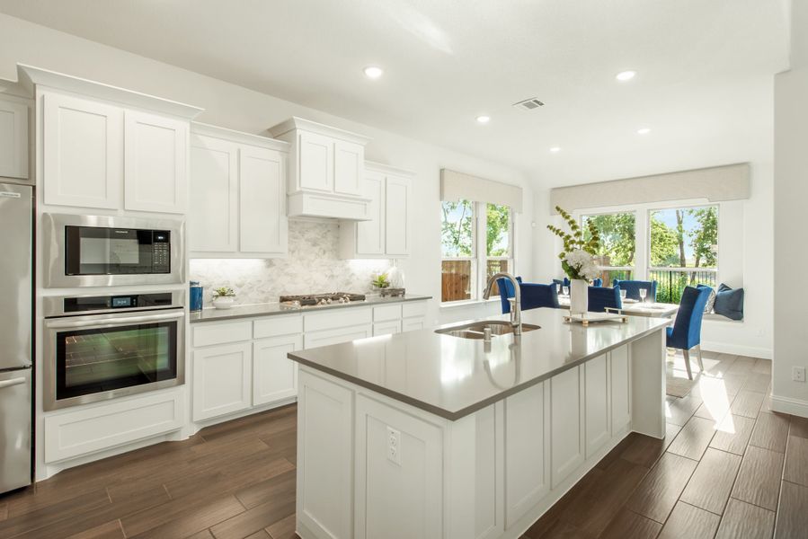 Kitchen with white cabinets, center island, stainless steel appliances, and open dining area with large windows