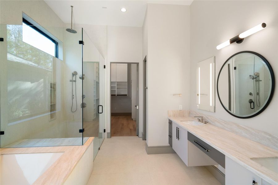 This modern bathroom features a spacious glass-enclosed shower, a large soaking tub, dual sinks with a sleek vanity, and ample natural light, providing a luxurious and serene atmosphere.