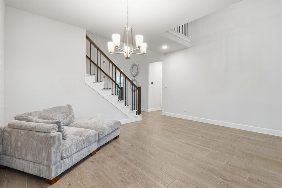 This modern living area features a sleek staircase with wooden railings, light hardwood floors, and a cozy gray sectional sofa. The space is bright and open, enhanced by a contemporary chandelier. This modern living area features a sleek staircase with wooden railings, light hardwood floors, and a cozy gray sectional sofa. The space is bright and open, enhanced by a contemporary chandelier.