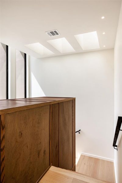 Staircase with recessed lighting, wood finished floors, and a skylight