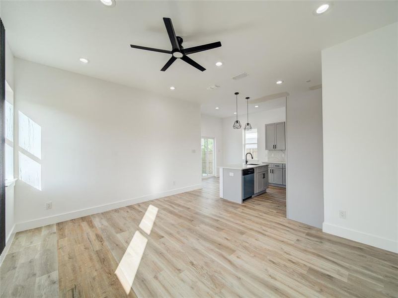 Unfurnished living room featuring ceiling fan, sink, and light hardwood / wood-style floors