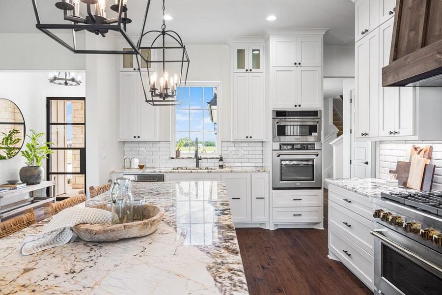 Kitchen with stainless steel appliances, light stone countertops, glass insert cabinets, white cabinets, and recessed lighting Kitchen with stainless steel appliances, light stone countertops, glass insert cabinets, white cabinets, and recessed lighting