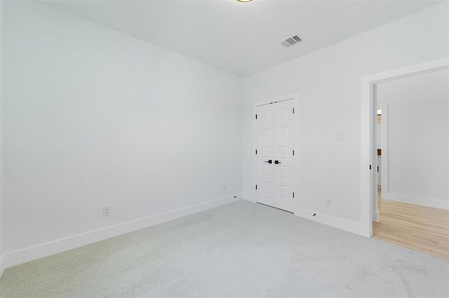 Unfurnished bedroom featuring light carpet and a closet