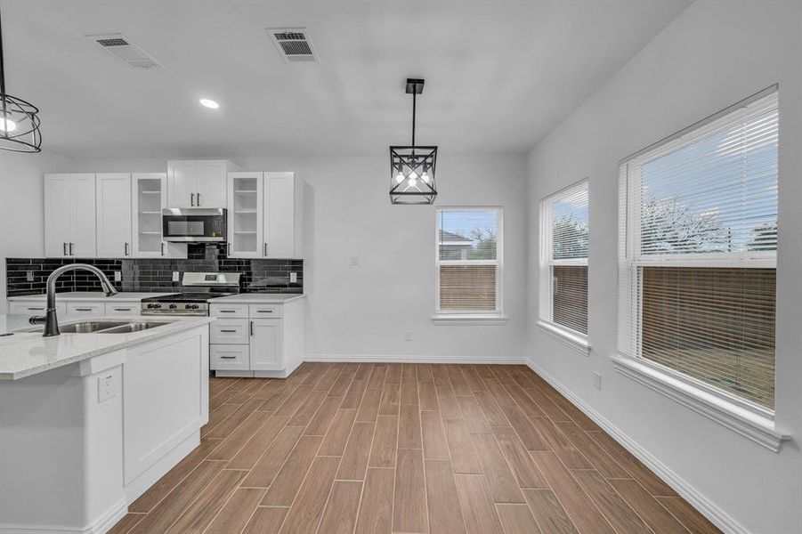 Kitchen featuring appliances with stainless steel finishes, sink, pendant lighting, and white cabinets