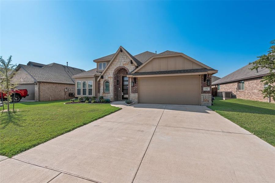 French country home with stone siding, a front lawn, a shingled roof, board and batten siding, and driveway French country home with stone siding, a front lawn, a shingled roof, board and batten siding, and driveway