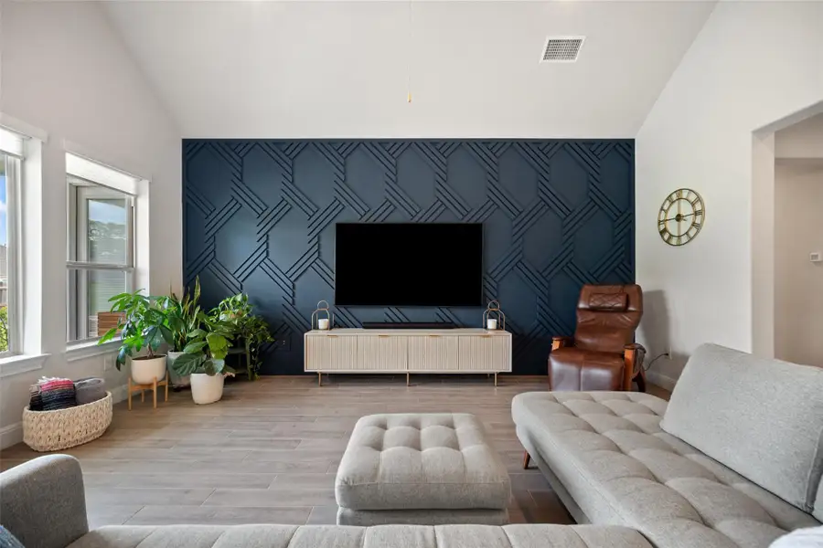 Living room featuring an accent wall, wood finished floors, high vaulted ceiling, and wallpapered walls