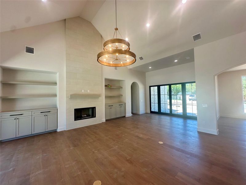 Rich hardwood flooring complements the soaring vaulted ceiling and stone fireplace in this great room.