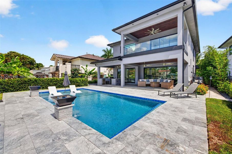 View from the new concrete dock and seawall to the Salt chlorinated pool w/ water features, LED color changing light, sun shelf with umbrella hole and in water stools. Stone decking surrounds the pool