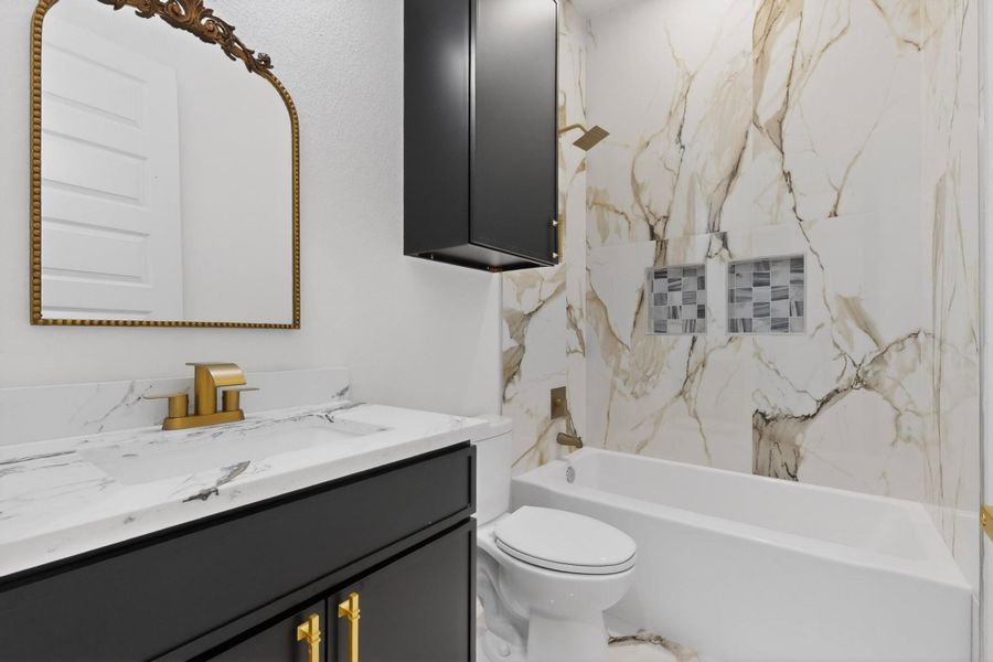 A well-appointed bath features a sleek vanity and an elegant shower with intricate tiling.