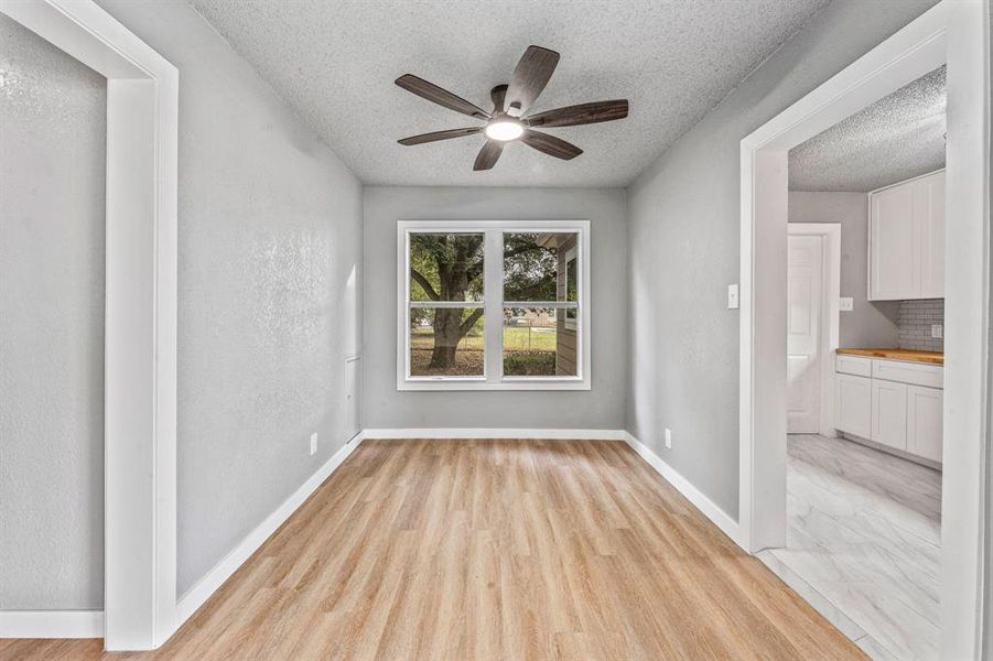 Spare room with a textured ceiling, a ceiling fan, and light wood-style flooring Spare room with a textured ceiling, a ceiling fan, and light wood-style flooring