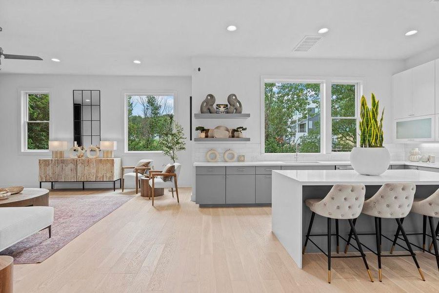 Kitchen featuring a breakfast bar, decorative backsplash, recessed lighting, light wood-style flooring, and light stone counters