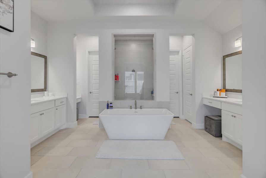 The primary suite includes a beautifully designed bathroom with dual vanities, a garden tub, a large glass-enclosed shower, and two walk-in closets for exceptional storage.