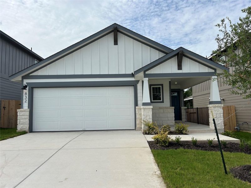 View of front facade featuring an attached garage, stone siding, concrete driveway, and a porch View of front facade featuring an attached garage, stone siding, concrete driveway, and a porch