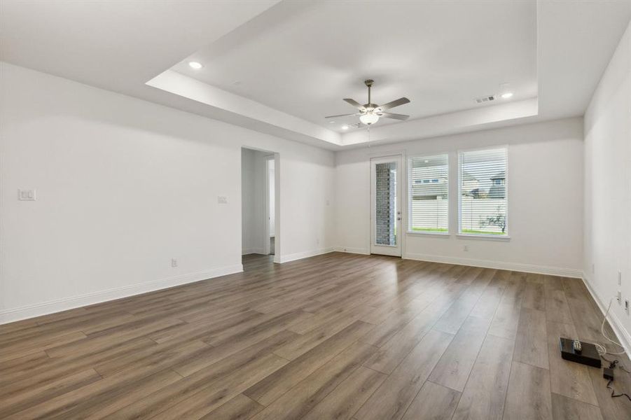 Empty room with a raised ceiling, ceiling fan, and hardwood / wood-style flooring