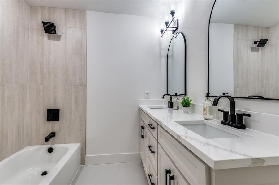 Full bathroom featuring washtub / shower combination, double vanity, and light tile patterned floors