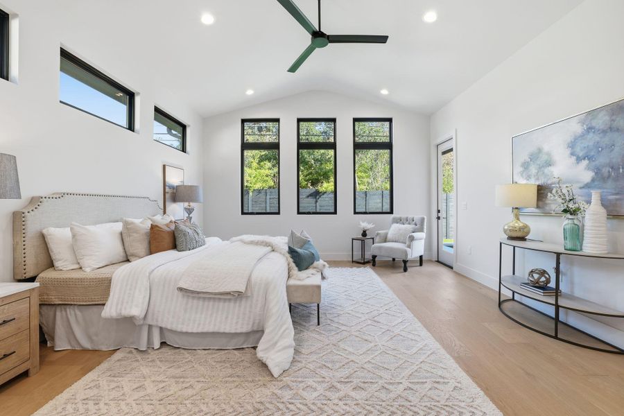 Bedroom featuring light wood-style flooring, multiple windows, access to outside, a ceiling fan, and lofted ceiling