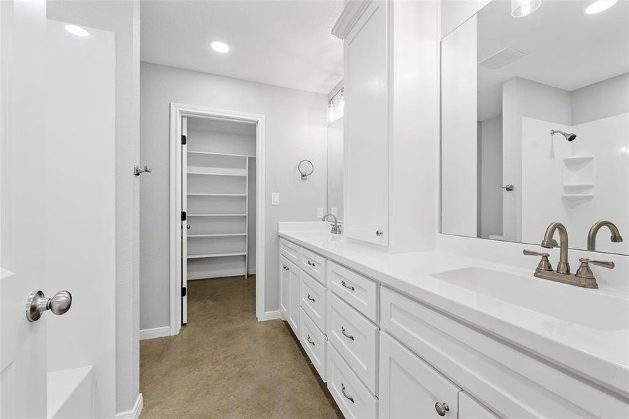 Bathroom with a shower, baseboards, concrete flooring, and a sink