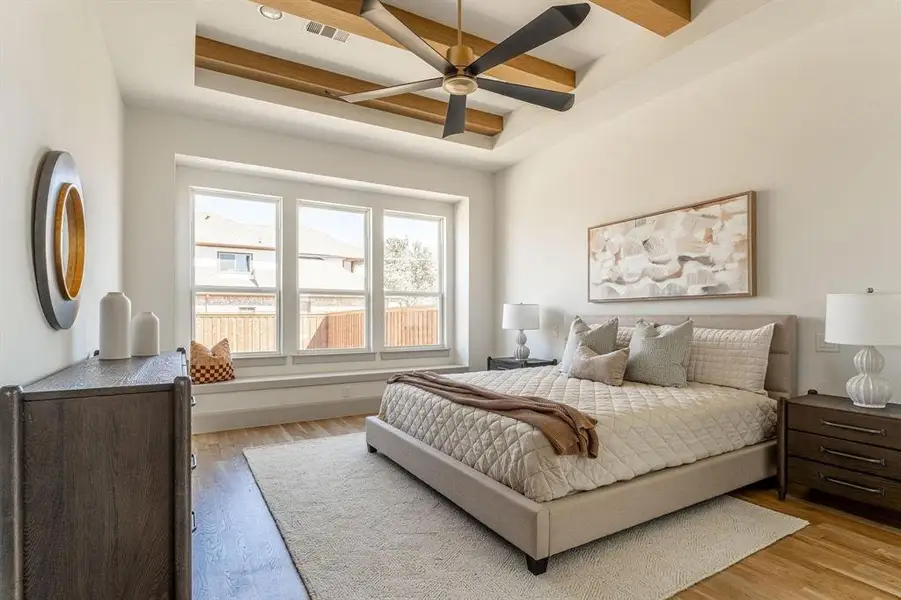Bedroom featuring a raised ceiling, wood finished floors, and ceiling fan