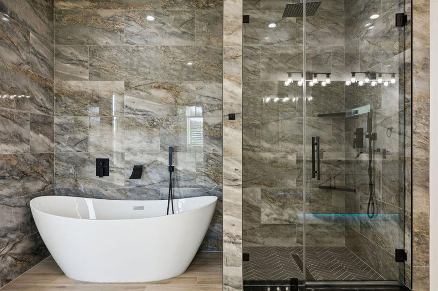 Bathroom with a soaking tub, a marble finish shower, and tile walls
