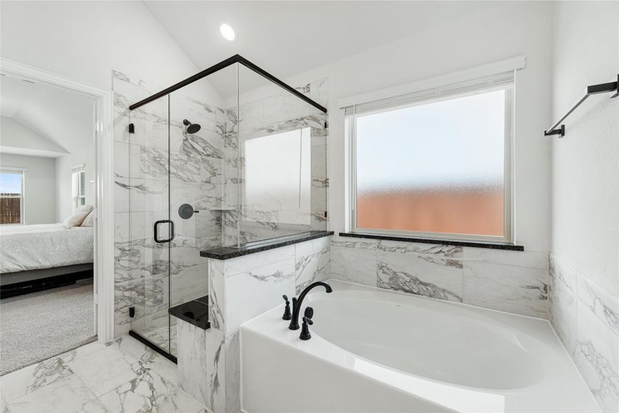 Master bathroom with marble tile, glass walk-in shower, soaking tub, and black fixtures