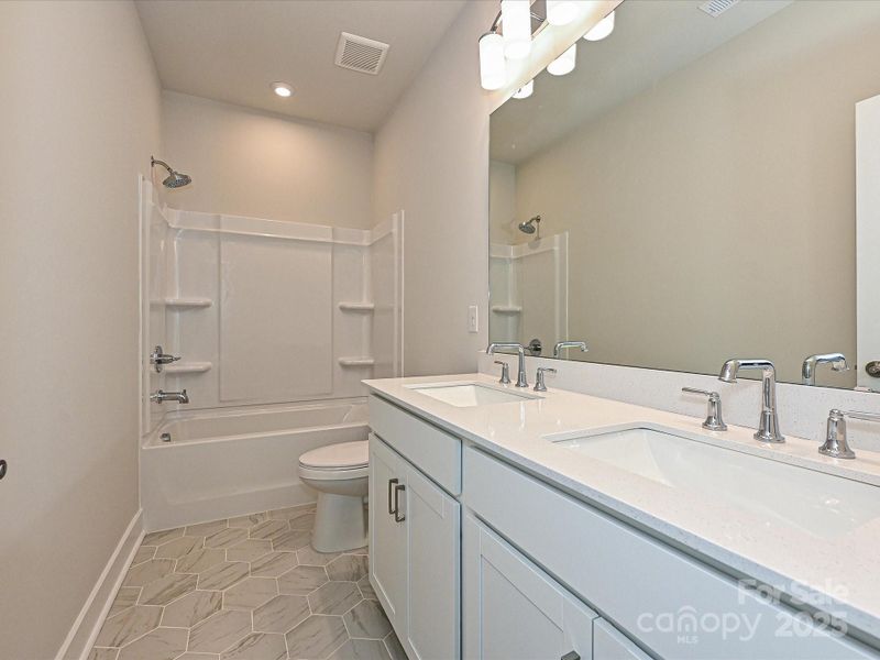 Secondary bathroom with modern tile and dual vanity.