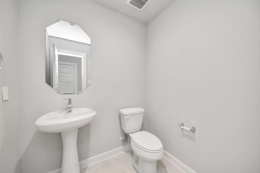 This half bathroom features a stylish pedestal sink, modern hardware, and bright recessed lighting, creating a sleek and inviting space. Sample photo of completed home with similar floor plan. Actual colors and selections may vary. This half bathroom features a stylish pedestal sink, modern hardware, and bright recessed lighting, creating a sleek and inviting space. Sample photo of completed home with similar floor plan. Actual colors and selections may vary.