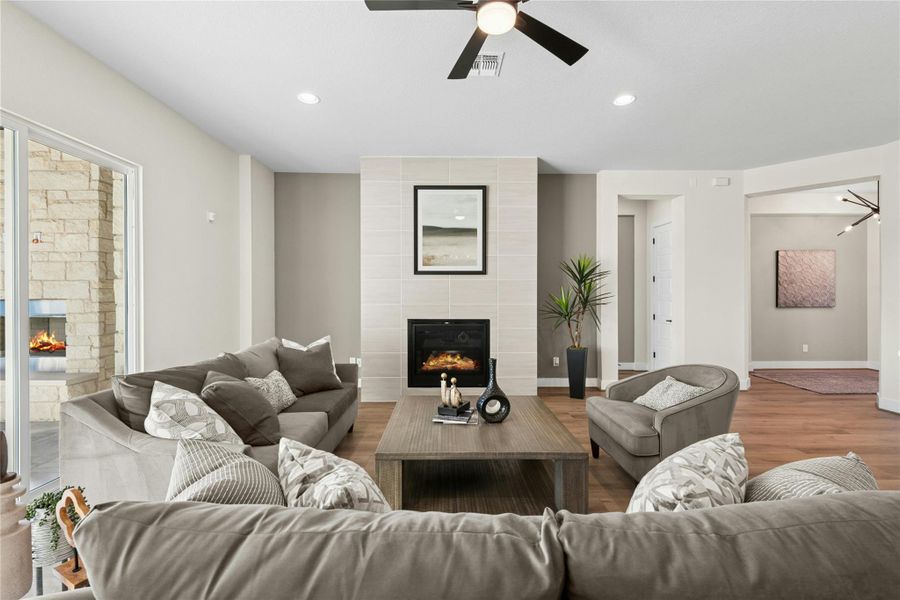Living room featuring a tiled fireplace, recessed lighting, wood finished floors, and a ceiling fan Living room featuring a tiled fireplace, recessed lighting, wood finished floors, and a ceiling fan