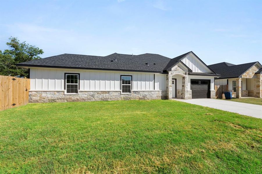 Modern inspired farmhouse featuring stone siding, roof with shingles, a garage, board and batten siding, and concrete driveway Modern inspired farmhouse featuring stone siding, roof with shingles, a garage, board and batten siding, and concrete driveway