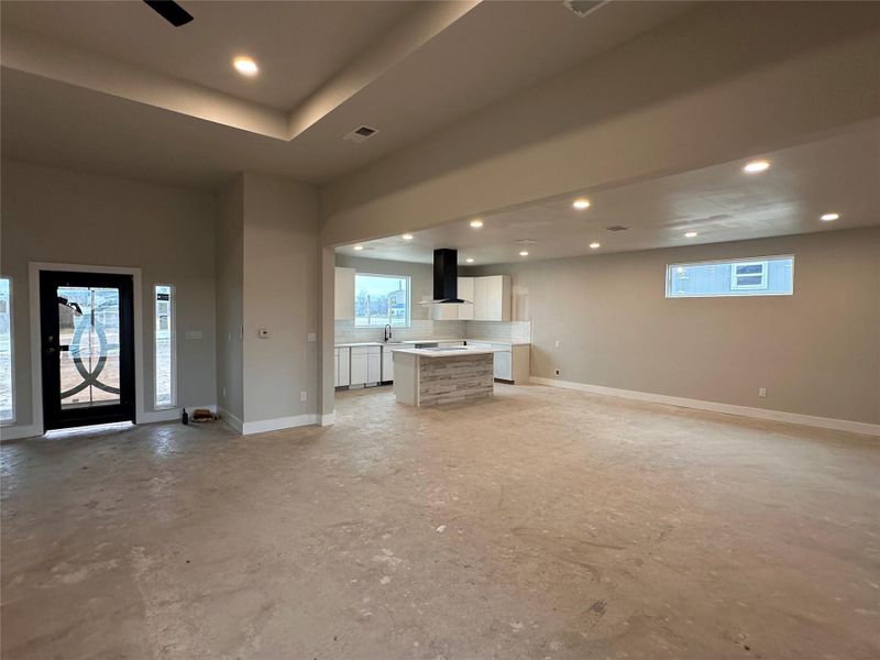 Unfurnished living room with recessed lighting, concrete floors, and a tray ceiling