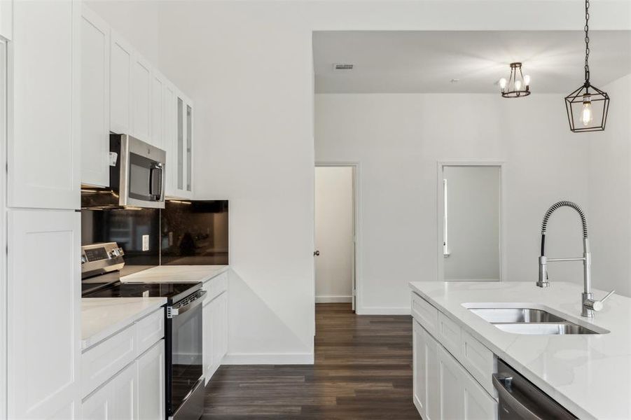 Kitchen featuring light stone counters, sink, stainless steel appliances, and white cabinets