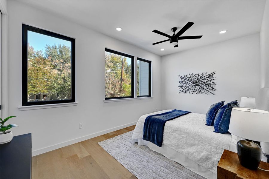 Bedroom with ceiling fan, multiple windows, and light hardwood / wood-style flooring