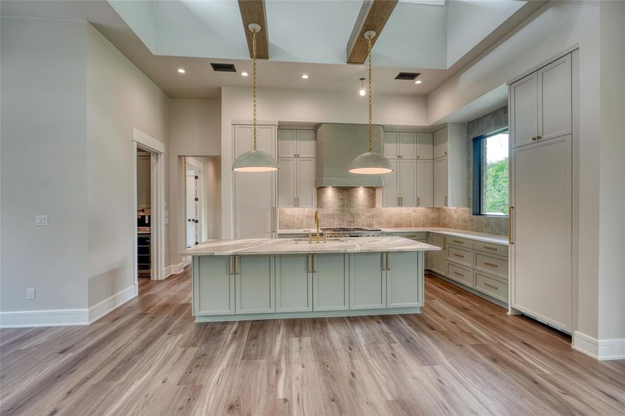 Kitchen featuring premium range hood, light wood-type flooring, backsplash, a kitchen island with sink, and recessed lighting