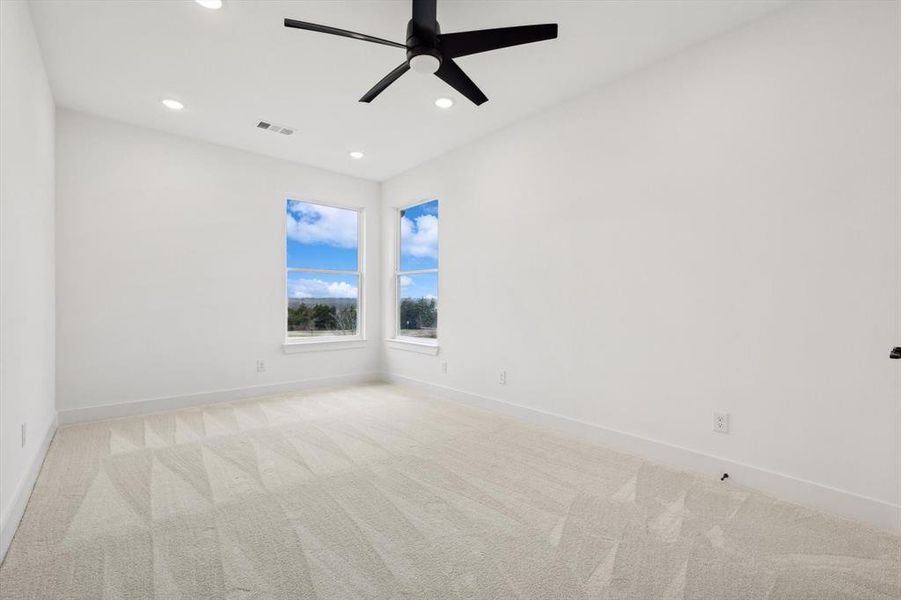 Empty room featuring light colored carpet and ceiling fan